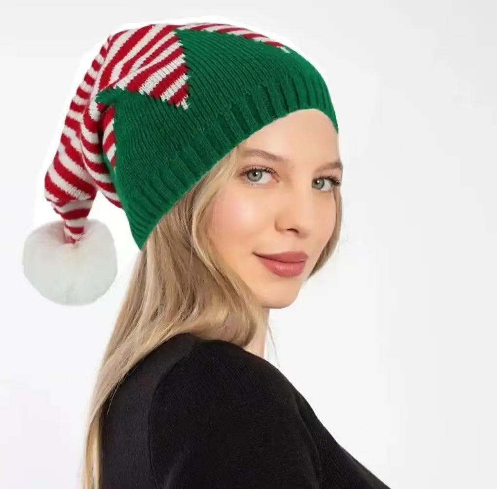 Woman wearing festive Christmas knit hat with red and white striped bow and green base"