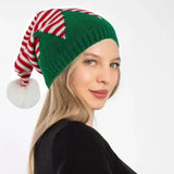 Woman wearing festive Christmas knit hat with red and white striped bow and green base"